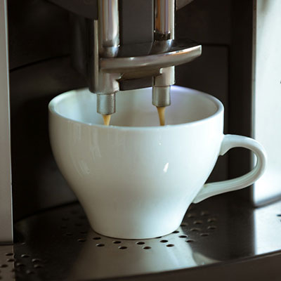 Eine Tsse, die von einem Kaffeevollautomaten mit Kaffee befüllt wird